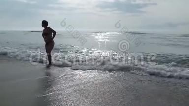 一位剪影中的女士欣赏着海滩上海水中的一个美丽而美丽的日出。
